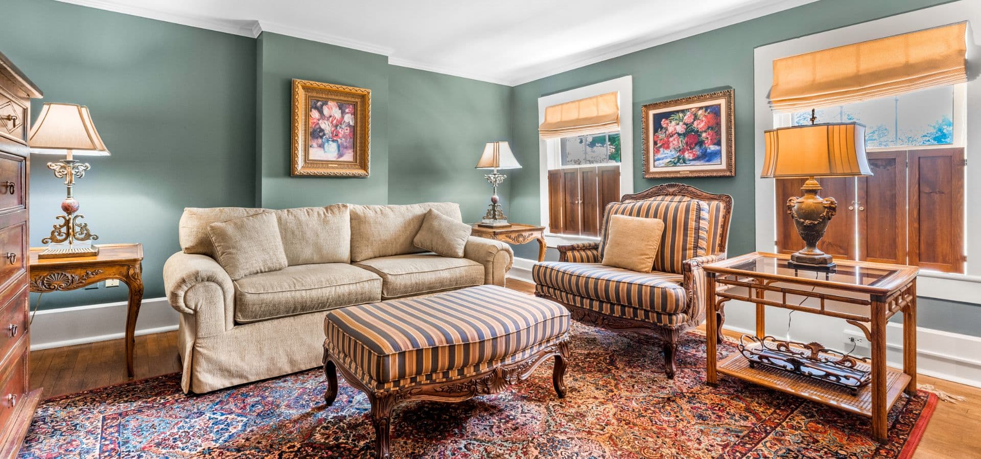 Cozy living room featuring a beige sofa, striped armchair, decorative rug, and wall artwork.